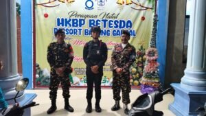 Petugas Banser dan Polri berpose bersama di depan spanduk perayaan Natal HKBP Bethesda Resort Batang Gansal. 