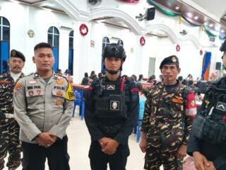 Personel gabungan Banser, Polri, dan Brimob berjaga di depan pintu masuk Gereja Bethesda Batang Gansal saat pengamanan malam Tahun Baru 2026.