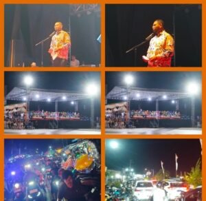 Foto jepretan Bupati Halmahera Selatan Hasan Ali Basam Kasuba (berpakaian batik/resmi) sedang menyampaikan sambutan di atas panggung yang dihiasi dekorasi adat/festival. Di latar belakang terlihat ribuan masyarakat Halmahera Selatan yang hadir dan antusias.