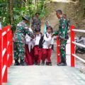 Satgas TMMD Kodim 0808 Blitar membantu siswa menyeberangi Jembatan Merah Putih di Desa Krisik