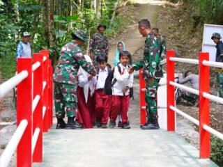 Satgas TMMD Kodim 0808 Blitar membantu siswa menyeberangi Jembatan Merah Putih di Desa Krisik