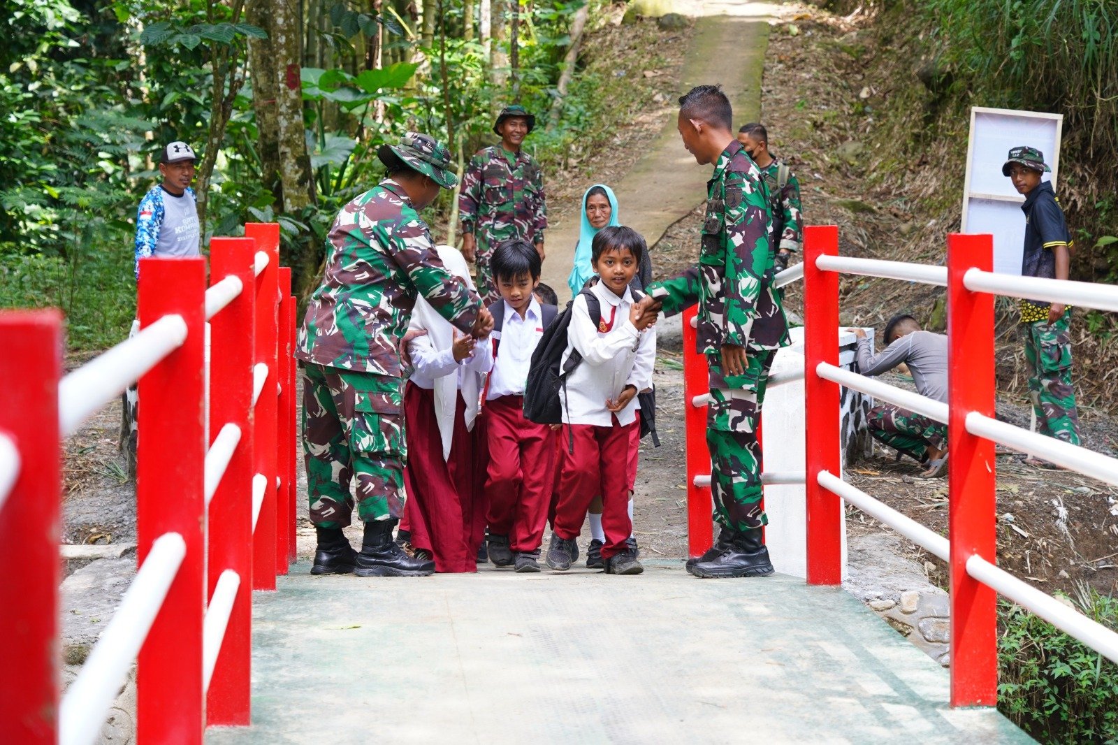 Satgas TMMD Kodim 0808 Blitar membantu siswa menyeberangi Jembatan Merah Putih di Desa Krisik