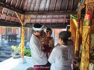 Orang tua menggendong bayi saat ritual tiga bulanan di Buleleng