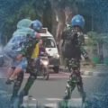 Prajurit Marinir TNI AL menggendong ibu lansia menyeberang jalan raya.