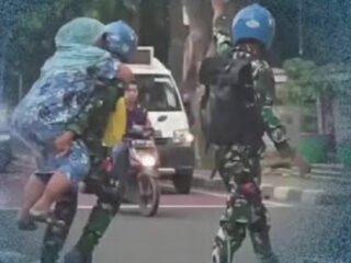 Prajurit Marinir TNI AL menggendong ibu lansia menyeberang jalan raya.