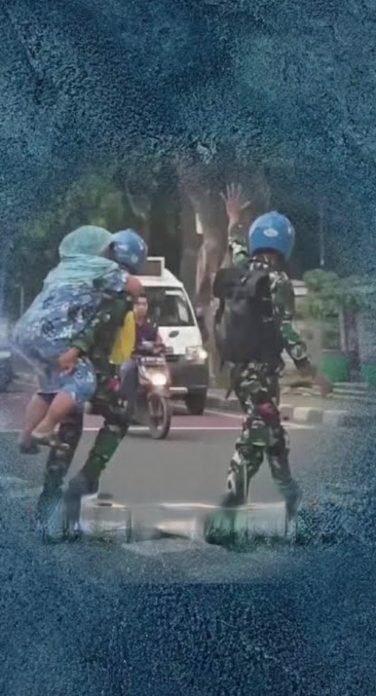 Prajurit Marinir TNI AL menggendong ibu lansia menyeberang jalan raya.