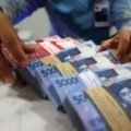 Petugas menunjukkan tumpukan uang rupiah untuk ilustrasi pencairan gaji ke-13 ASN tahun 2026