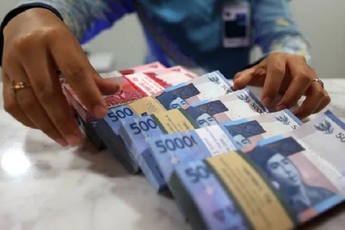 Petugas menunjukkan tumpukan uang rupiah untuk ilustrasi pencairan gaji ke-13 ASN tahun 2026