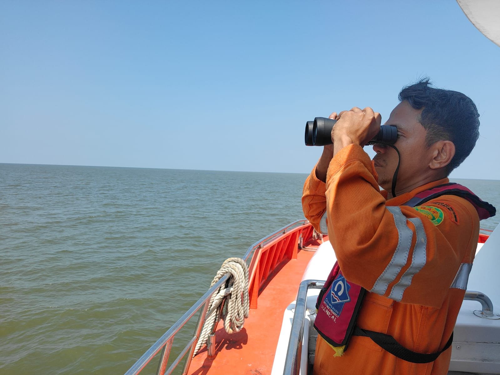 Lapal TKI Tenggelam Petugas SAR mengamati perairan menggunakan teropong dari atas kapal pencarian di perairan Rupat.